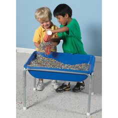 two young boys playing in a blue sand and water table with sprinkles