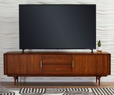 a flat screen tv sitting on top of a wooden entertainment center next to a rug