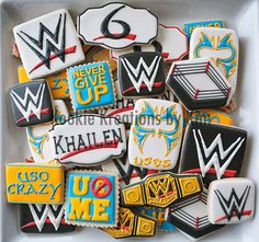 decorated cookies in the shape of wwe logos on a white platter with black, yellow and blue icing