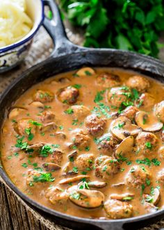 a skillet filled with meatballs and gravy next to mashed potatoes