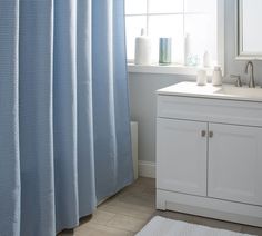 a bathroom with a blue shower curtain next to a white sink