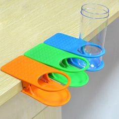 three pieces of plastic cutting board sitting on top of a wooden table next to a cup