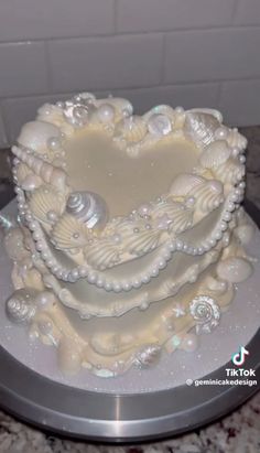 a heart shaped cake with seashells and pearls on it's sides is sitting on a silver platter