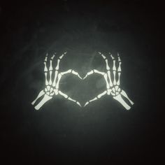 two hands making a heart shape in the dark