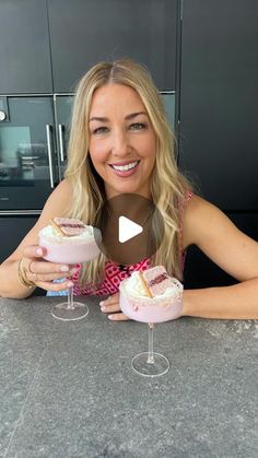 a woman sitting at a table with two desserts in front of her and smiling