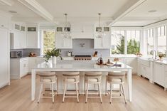 a large kitchen with white cabinets and counter tops, along with an island in the middle