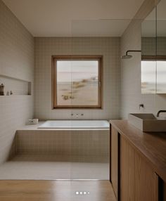 a bathroom with a tub, sink and large window in the corner on the wall