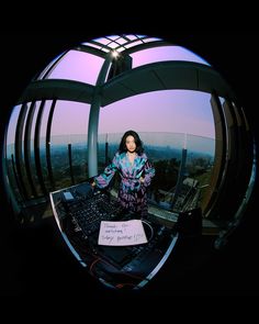 a woman standing in front of a dj's mixing desk on top of a building