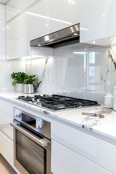 a stove top oven sitting inside of a kitchen next to white cabinets and counter tops