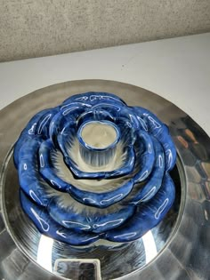 a blue and white flower shaped bowl on top of a silver plate