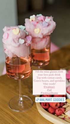 two glasses filled with pink liquid and topped with marshmallows on a wooden table