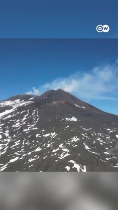 an aerial view of a mountain with snow on the ground and clouds in the sky