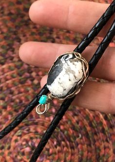 "A very unique bolo slide, completely handmade from high quality stock. Otteson-mined, \"White Buffalo\" Stone & vintage Sleeping Beauty\" turquoise are nestled in a rustic braided setting made of American made Sterling Silver. 3 thick strands of 16 gauge 1/2 round sterling silver wire are freely braided and shaped to create a rustic woven bezel. At the bottom is a classic 6x4mm basket setting. Soldered for strength & durability. On the back, a vintage steel bolo slide accommodates any 4-5mm cor Custom Handmade White Jewelry, Artisan Adjustable Untreated Jewelry, Untreated Adjustable Artisan Jewelry, Handmade Bohemian Bolo Tie, Handmade Southwestern Turquoise Bolo Ties, Handmade Artisan Turquoise Bolo Ties, Artisan Handmade Turquoise Bolo Ties, One Of A Kind Adjustable Western Jewelry, Unique Handmade Lariat Bolo Ties