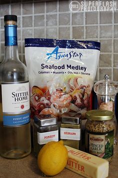 ingredients to make shrimp salad laid out on a kitchen counter with bottle of wine, salt and pepper