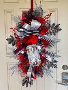 a red and silver christmas wreath hanging on a door