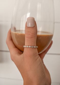 a woman's hand holding a wine glass with a ring on it