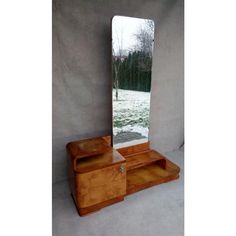 a mirror sitting on top of a wooden dresser next to a wall with a tree in the background