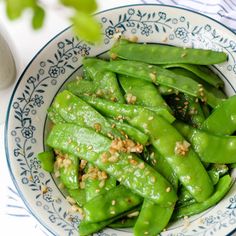 a bowl filled with green beans on top of a table