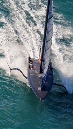 an aerial view of a sailboat in the middle of the ocean with water splashing behind it