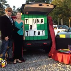 a man and woman standing in front of a trunk to treat truck at an outdoor event