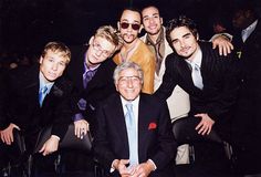 a group of men in suits and ties posing for a photo with one man wearing glasses