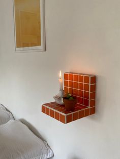 a candle that is sitting on top of a shelf next to a bed in a room