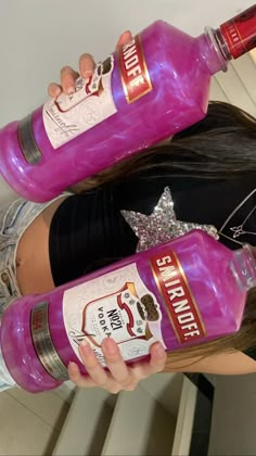 two girls are holding up pink liquor bottles