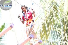 a girl on a rope course with palm trees in the background