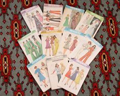 six vintage sewing patterns are laid out on a colorful rug, with the same pattern in different colors and sizes