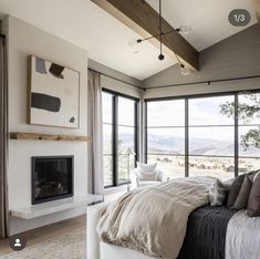 a large bed sitting in the middle of a bedroom next to a fireplace and windows