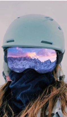 a person wearing a helmet and goggles with the reflection of mountains in their glasses