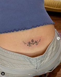 a woman's stomach has a small tattoo on her lower side ribcage