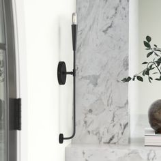 a vase sitting on top of a marble shelf next to a clock and door handle