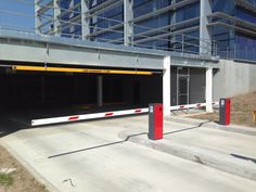 an empty parking garage in front of a building with red and white striped railings