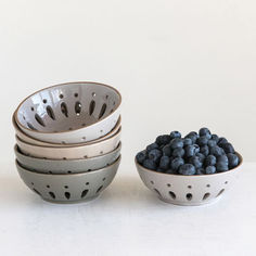 four bowls filled with blueberries sit next to each other on a white countertop