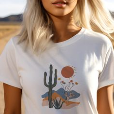 Immerse yourself in the rugged beauty of the West with our Cactus Desert with Wildflowers T-Shirt. This stunning design captures the essence of the desert, featuring a striking cactus landscape adorned with vibrant wildflowers. Crafted in desert-inspired colors, this tee is a perfect choice for those who appreciate the untamed allure of the Western frontier. This Cactus Desert with WildFlowers T-Shirt features a unique and eye-catching design that is perfect for both men and women. Made with high-quality jersey material, this short sleeve tee offers comfort and style. Stand out from the crowd with this one-of-a-kind shirt. #25 Classic unisex jersey short sleeve tee fits like a well-loved favorite. Soft cotton and quality print make users fall in love with it over and over again. Ribbed kni Cactus Landscape, Western Frontier, Cactus Desert, Western Tee, Desert Flowers, The Untamed, Prism Color, The Desert, Irritated Skin