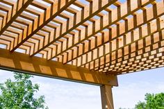 a wooden pergolated roof with trees in the background