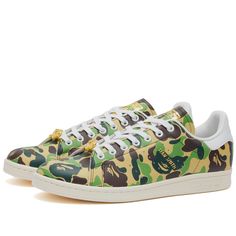 Find ADIDAS X Bape Stan Smith Sneakers on Editorialist. Lace up in a piece of streetwear history with these reimagined Stan Smith sneakers from adidas and BAPE’s latest collaboration. Wrapped in the iconic ABC Camo print, they pay homage to BAPE's coveted streetwear identity. Co-branded gold detailing feature throughout the anticipated design, forgoing the usual Stan Smith portrait for BAPE’s cult-favourite ape head on the tongue. A clean off-white sole underfoot rounds off the limited-edition r Adidas Low-top Custom Sneakers For Skateboarding, Adidas Sneakers With Vulcanized Sole For Streetwear, Urban Adidas Low-top Custom Sneakers, Adidas Lace-up Skate Shoes For Streetwear, Urban Low-top Custom Adidas Sneakers, Adidas Low-top Sneakers For Streetwear, Adidas High-top Sneakers With Vulcanized Sole For Streetwear, Green Graphic Print Sports Sneakers, Adidas Logo Custom Low-top Sneakers For Streetwear