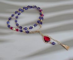 This exquisite one-of-a-kind necklace showcases the elegance of lavender elongated crystal beads, paired beautifully with vibrant fuchsia bicone crystals and luxurious gold accents. The necklace features a stunning dual pendant design with a large 13x18 mm fuchsia teardrop crystal and a delicate gold tassel, adding a touch of sophistication and movement. The gold hardware is finished with a durable 24-karat gold plating, ensuring both beauty and longevity. Measuring 42 cm in length with an addit Crystal Bead Necklace, Pendant Design, Minimalist Jewelry, Gold Beads, Bead Necklace, Gold Accents, Crystal Beads, Gold Hardware, Favorite Jewelry