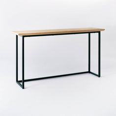 a wooden table with black metal legs on a white background in front of a wall