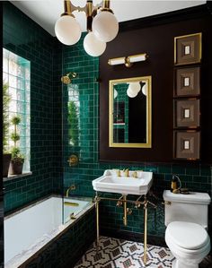 a green tiled bathroom with gold fixtures and white toilet, sink, and bathtub