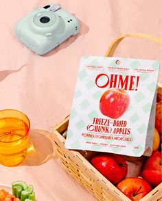 a camera and some fruit in a basket on a pink table with a sign that says ohme