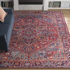 a living room with a blue couch and red rug in front of a tv set