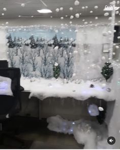 an office cubicle decorated with snow and christmas decorations on the walls, along with two computer desks