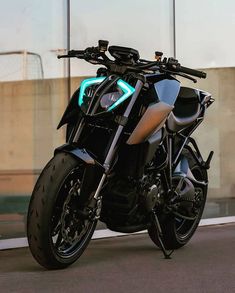 a black motorcycle parked in front of a building with its light up on it's side