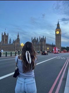 a woman standing in front of big ben and the houses of parliament at dusk, london