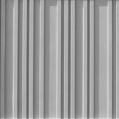 a black and white photo of the side of a building with vertical lines painted on it