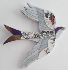 a decorative bird made out of paper on a white wall