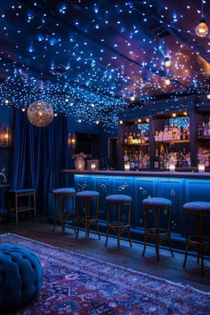 a dimly lit bar with stools and lights on the ceiling, in front of blue curtains