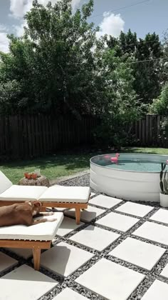 a dog laying in the middle of a patio next to a hot tub and chaise lounge